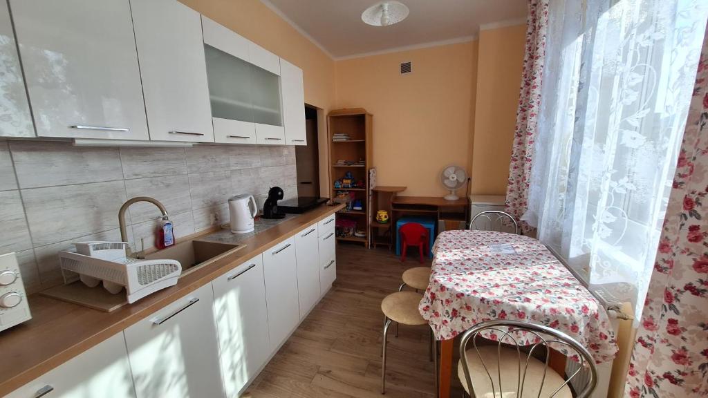 een keuken met witte kasten en een tafel en een kruk bij Mieszkanko na peryferiach in Chrzanów