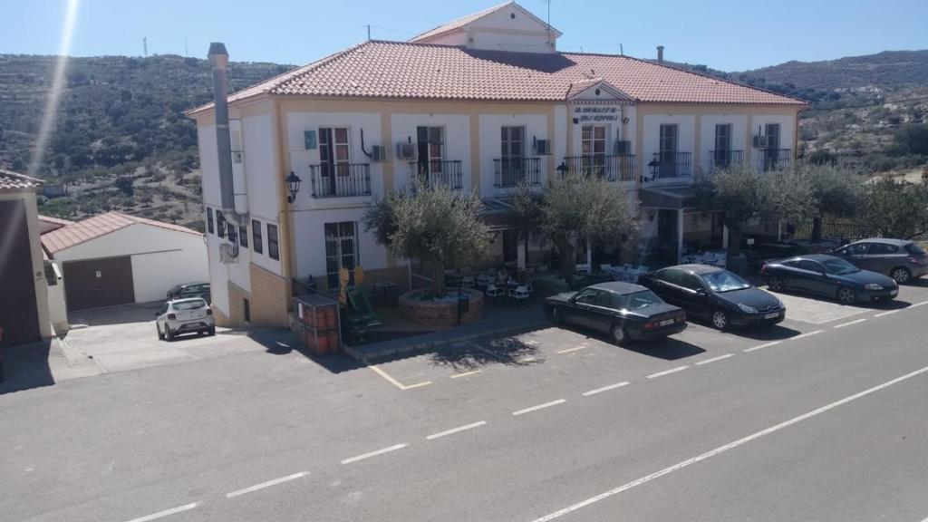 un gran edificio blanco con coches aparcados en un aparcamiento en Hotel Rural-Restaurante Los Olivos, en Almería