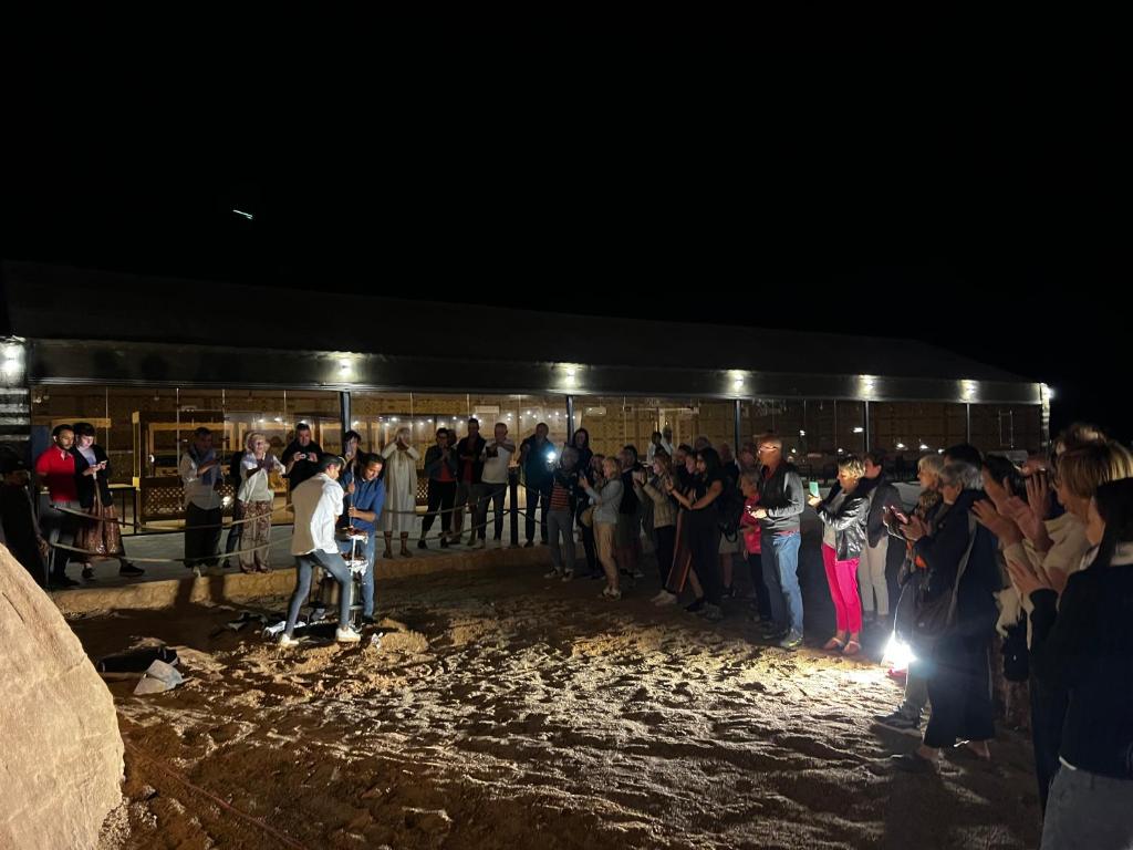 une foule de personnes debout devant un bâtiment la nuit dans l'établissement Victoria Desert Camp, à Disah