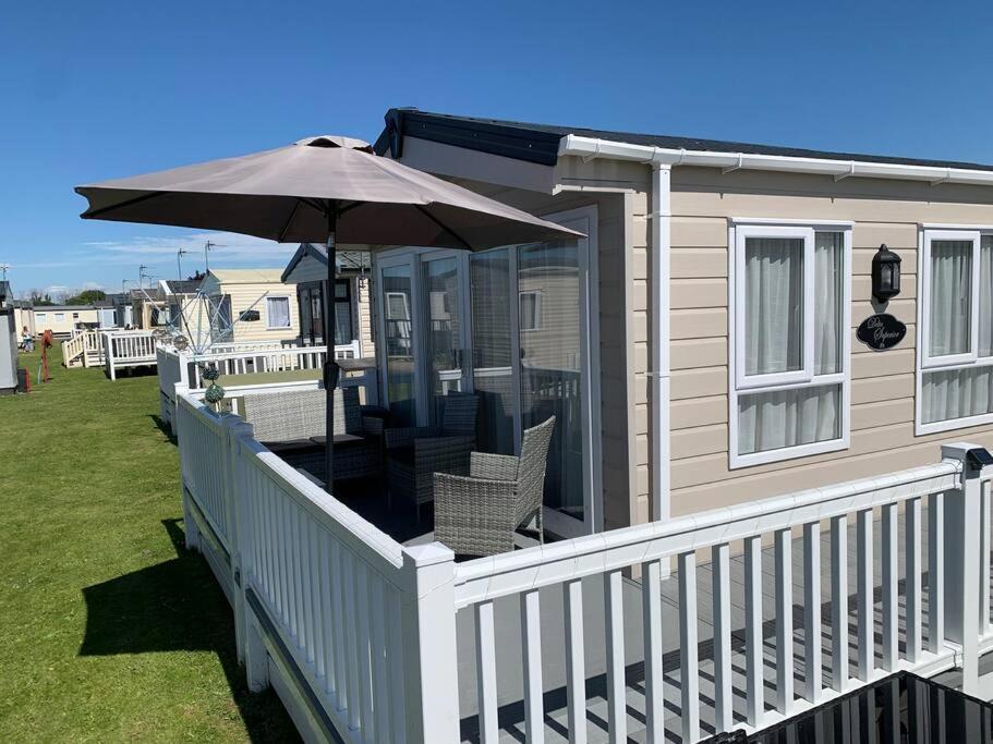 Casa con porche con sombrilla y sillas en 6 berth luxury caravan, Lyons Winkups Holiday Park, en Kinmel Bay