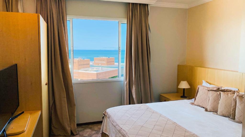 a hotel room with a bed and a large window at Hotel Atlantico Macaé By Inn House in Macaé