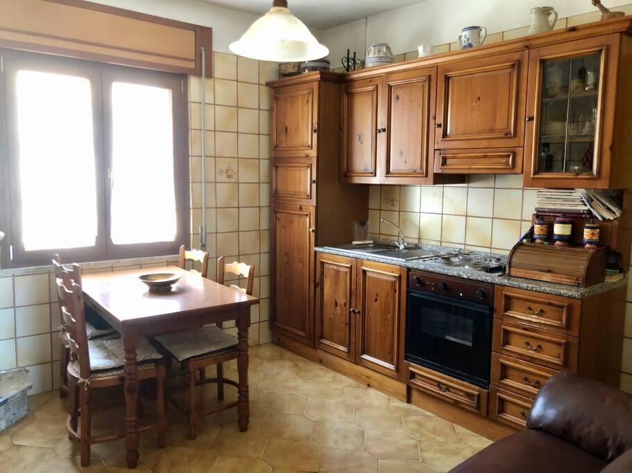 una cocina con armarios de madera y una mesa de madera y una mesa y un taburete en Appartamento nel cuore della Basilicata, en Ruvo del Monte