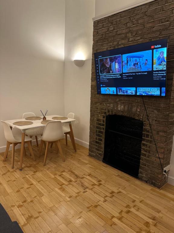 uma sala de estar com uma mesa e uma televisão numa lareira de tijolos em Excellent 1 bedroom flat in Highbury & Islington em Londres