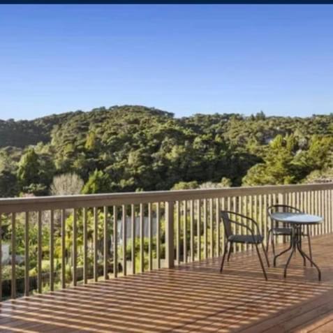 a table and a chair on a deck with a mountain at Paihia Retreat in Paihia