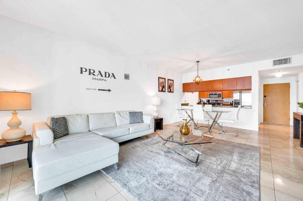 a living room with a white couch and a kitchen at Modern 1 Bed in the Heart of Brickell With Free Parking in Miami
