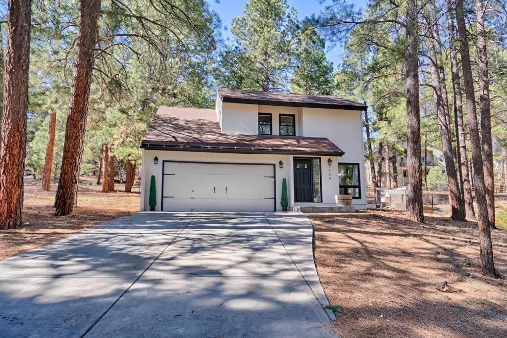 uma casa branca com uma garagem na floresta em Quaint home in the Pines em Flagstaff