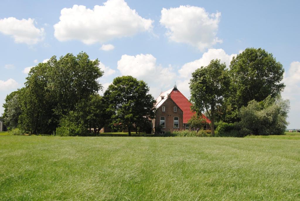 a house with a red roof in a field at Appartementen verhuur De Trijehoek in Stiens