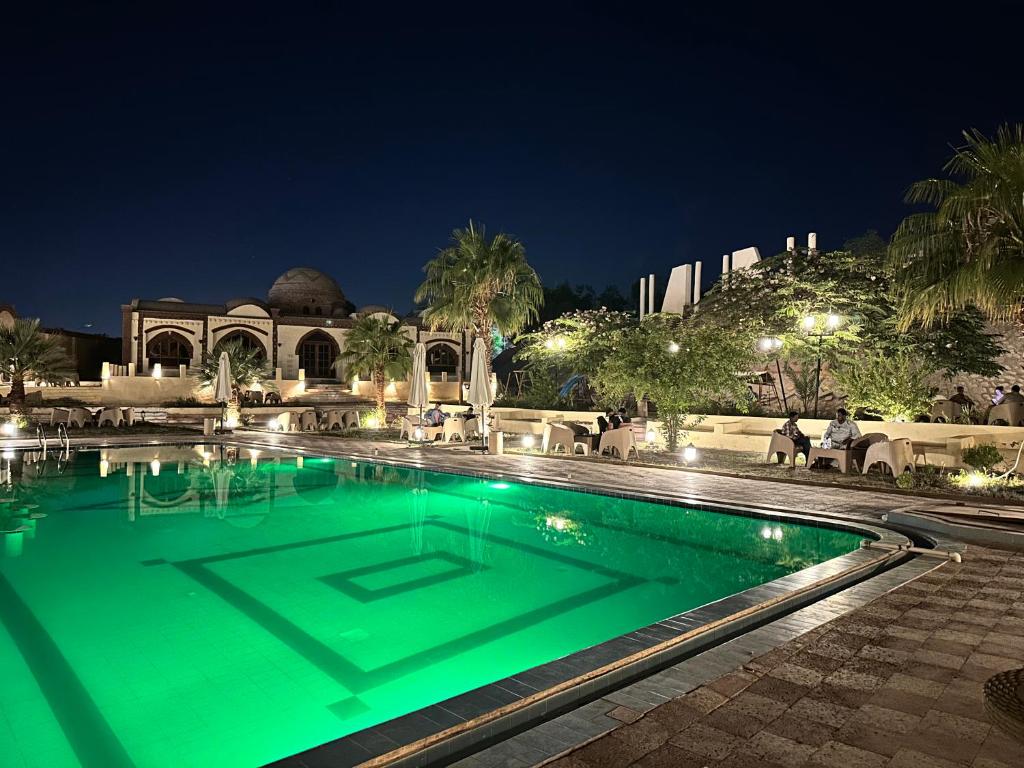 Elphardous Oasis Hotel في الأقصر: حمام سباحة مع إضاءة خضراء في الليل