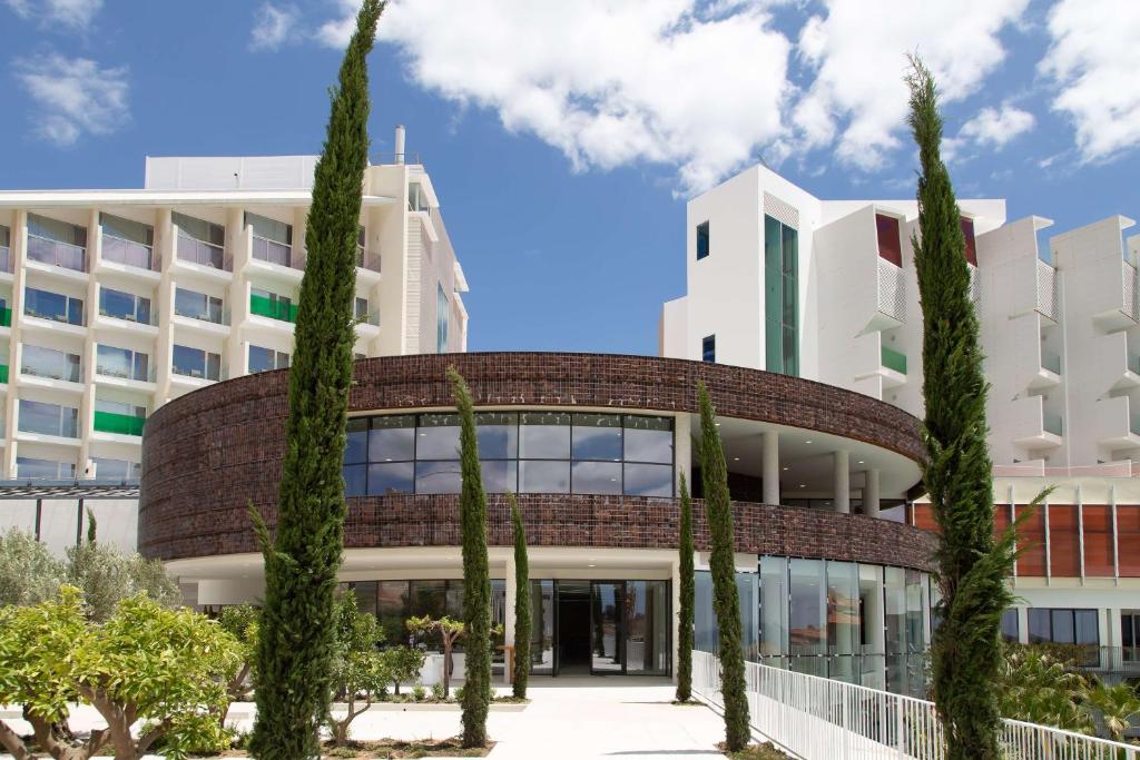 um edifício de escritórios com árvores em frente em Higuerón Hotel Curio Collection by Hilton em Fuengirola