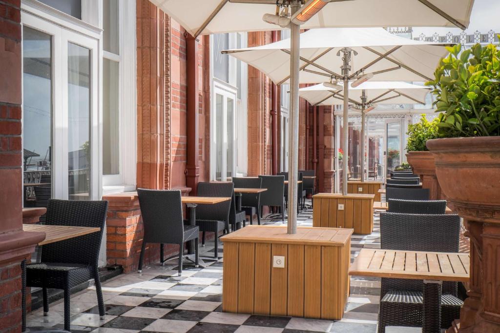 a restaurant with tables and chairs and umbrellas at DoubleTree By Hilton Brighton Metropole in Brighton & Hove