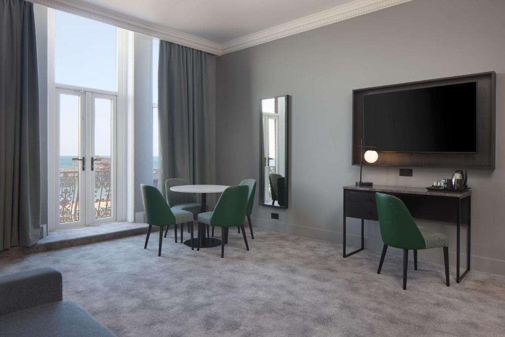 a living room with a table and chairs and a television at DoubleTree By Hilton Brighton Metropole in Brighton & Hove