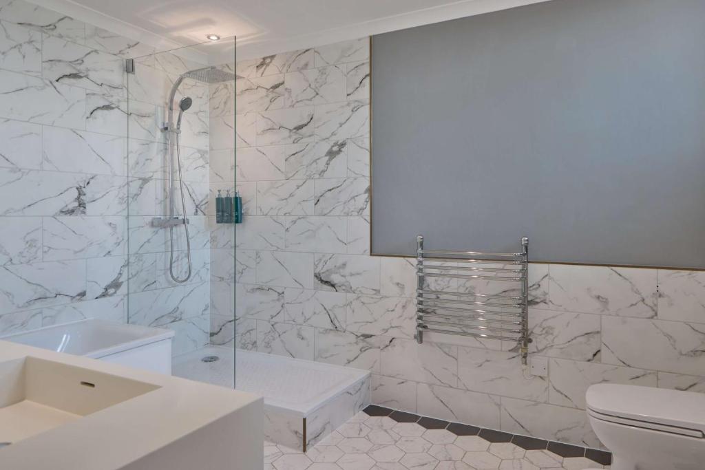 a white bathroom with a shower and a toilet at DoubleTree By Hilton Brighton Metropole in Brighton & Hove