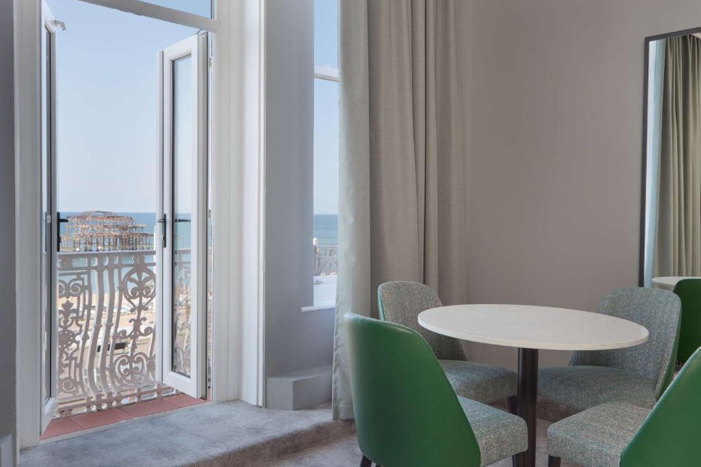 a room with a table and chairs and a balcony at DoubleTree By Hilton Brighton Metropole in Brighton & Hove