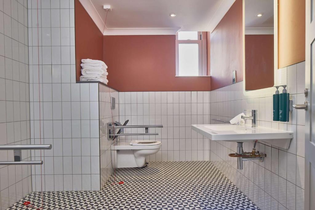 a bathroom with a toilet and two sinks at DoubleTree By Hilton Brighton Metropole in Brighton & Hove