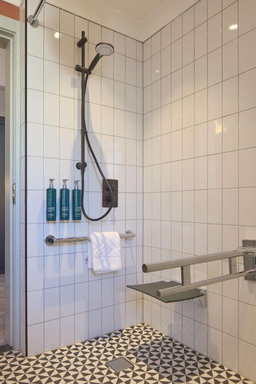 a bathroom with a shower with white tiles at DoubleTree By Hilton Brighton Metropole in Brighton & Hove