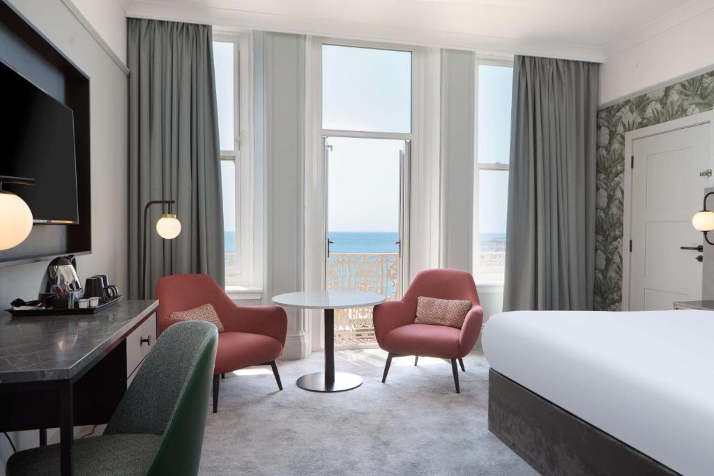 a hotel room with a bed and a table and chairs at DoubleTree By Hilton Brighton Metropole in Brighton & Hove