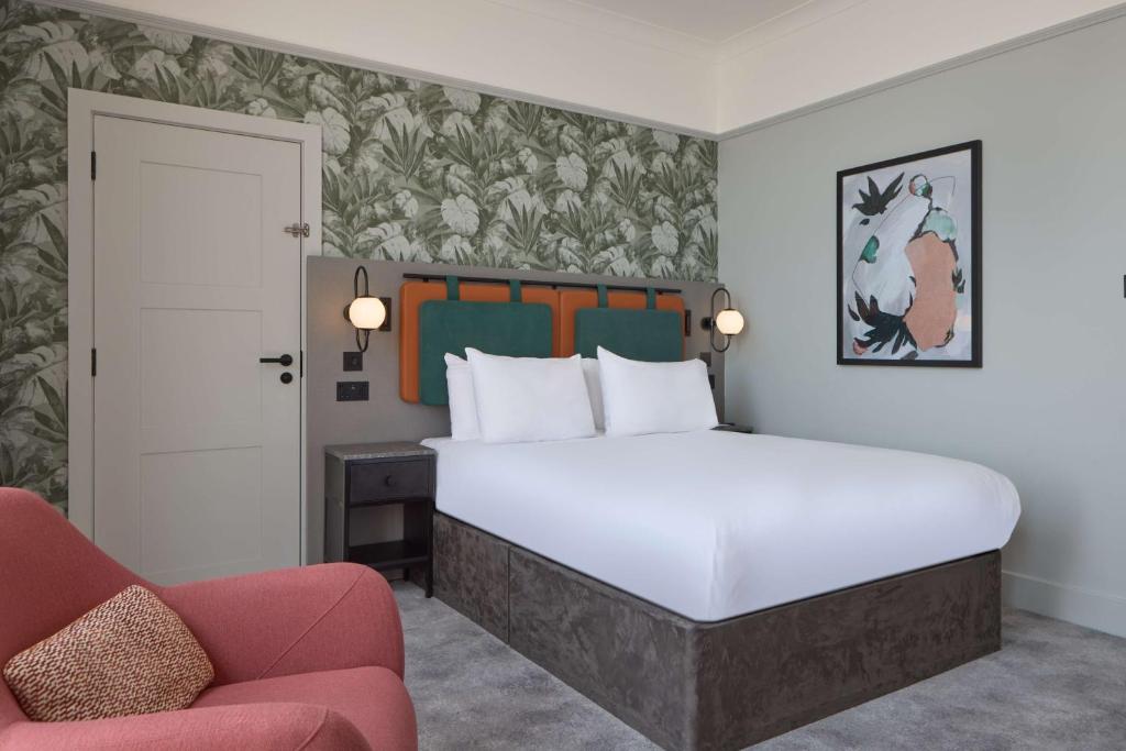 a bedroom with a large white bed and a chair at DoubleTree By Hilton Brighton Metropole in Brighton & Hove