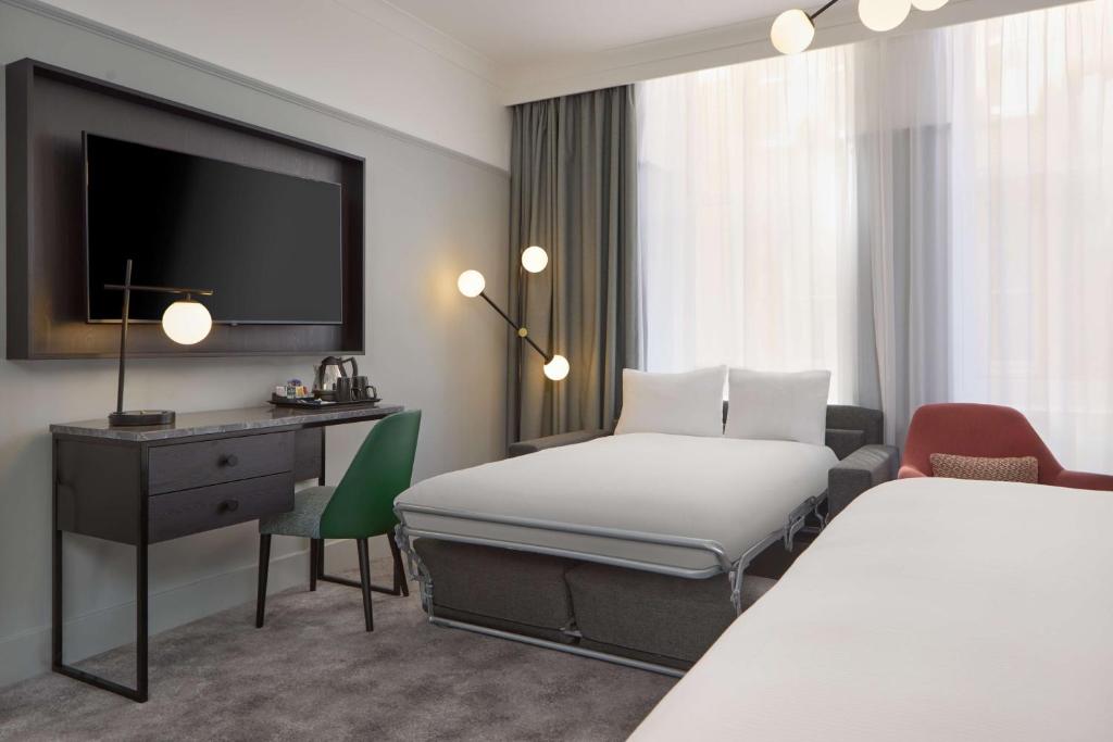 a hotel room with a bed and a desk and a tv at DoubleTree By Hilton Brighton Metropole in Brighton & Hove