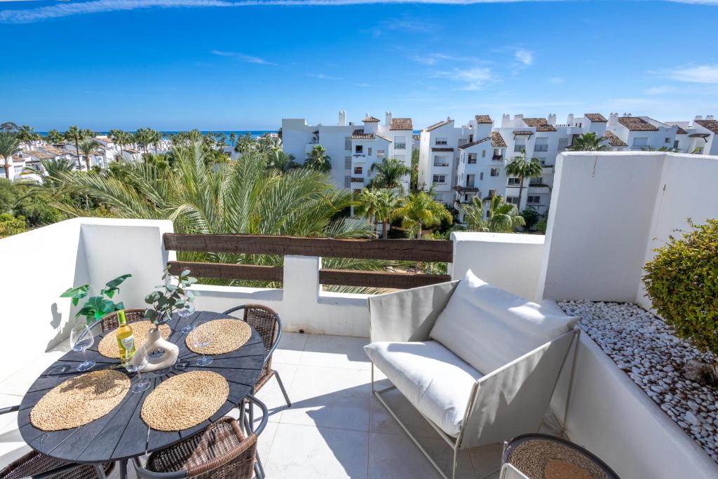 uma varanda com mesas e cadeiras e vista para o oceano em Top floor spacious apartment with sea views in Costalita em Estepona