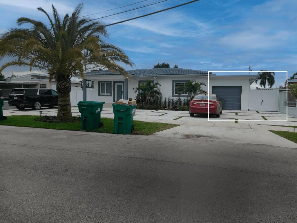 a house with a palm tree and two trash cans at 1BR Downtown Apt Sleeps 3, Modern Bath & Kitchen L10B in Miami