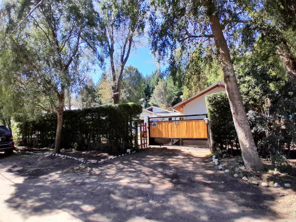 uma cerca em frente a uma casa com árvores em Casa con jardín - Circuito Chico, Bariloche em San Carlos de Bariloche