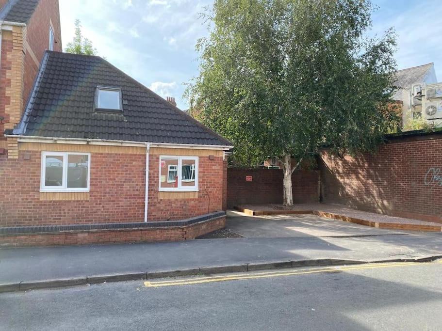 a red brick house with a tree in front of it at Stylish Property in Nuneaton in Nuneaton