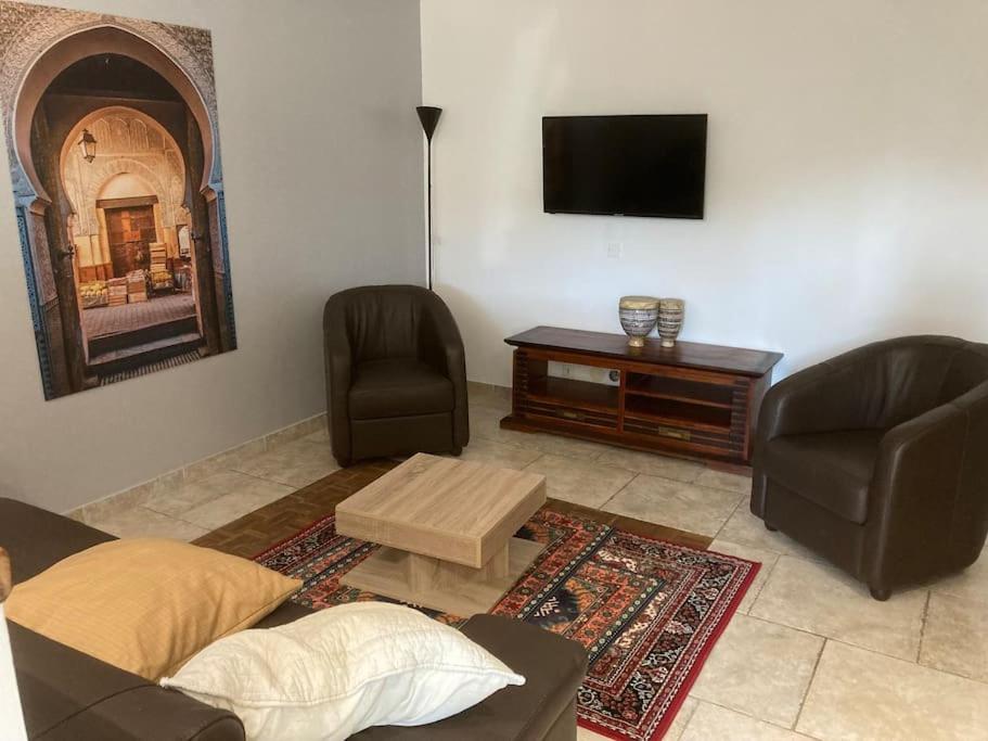 Appartement «Marrakech » à Avignon في أفينيون: غرفة معيشة مع أريكة وكرسيين وتلفزيون
