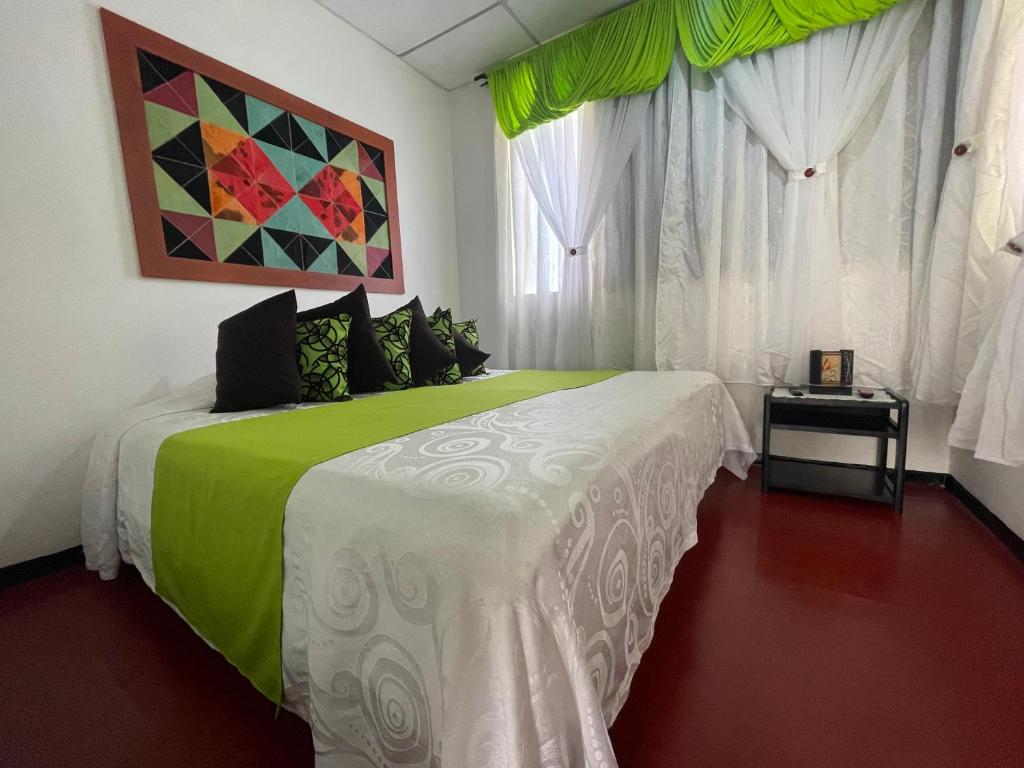 - une chambre avec un lit vert et blanc et des fenêtres dans l'établissement LA ESTIBA HOTEL, à Salento