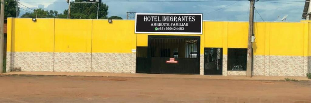 a yellow and white building with a sign on it at Hotel Imigrantes - Várzea Grande in Várzea Grande