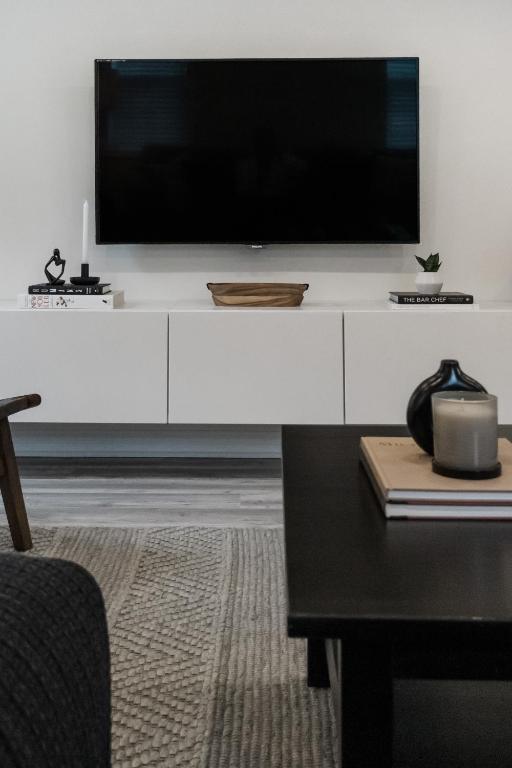 a living room with a large television on a white cabinet at The Little White Haus in Niagara-on-the-Lake