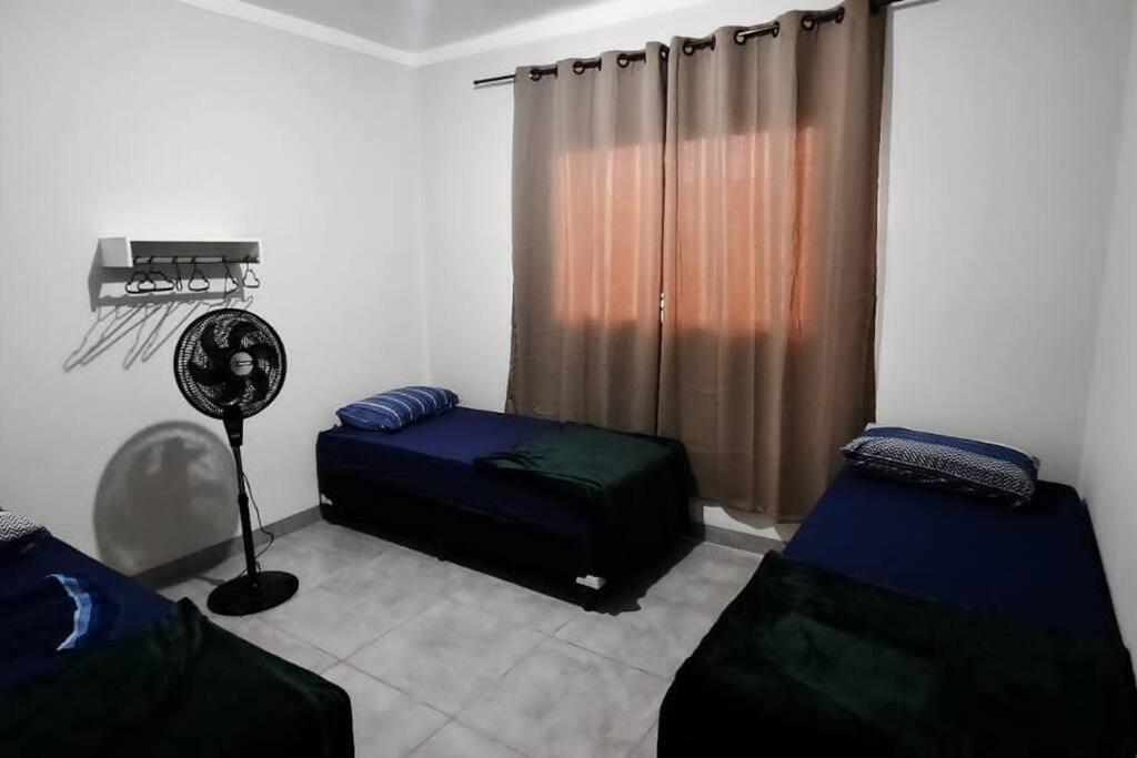 Pokój z 2 łóżkami, wentylatorem i oknem w obiekcie North Park 388 w mieście Campo Grande