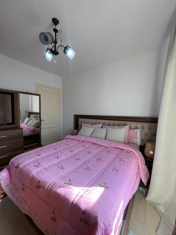 ein Schlafzimmer mit einem rosa Bett und einem Spiegel in der Unterkunft Grand Madinaty Couzy Home in Madinaty