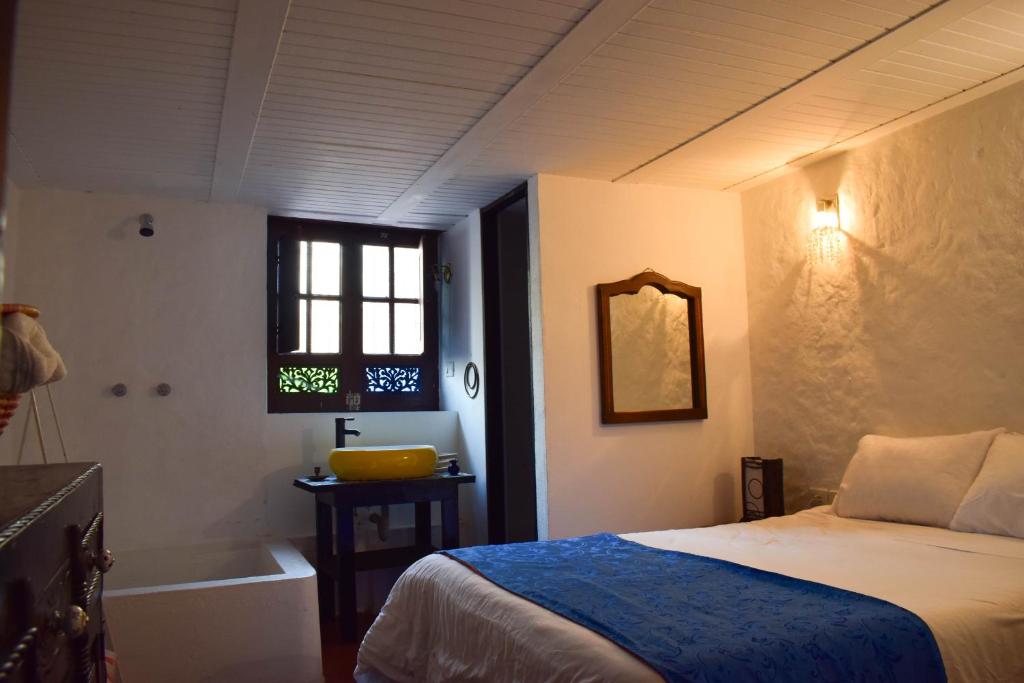 a bedroom with a bed and a tub and a window at HOTEL CHORRO DE LUZ in Bogotá