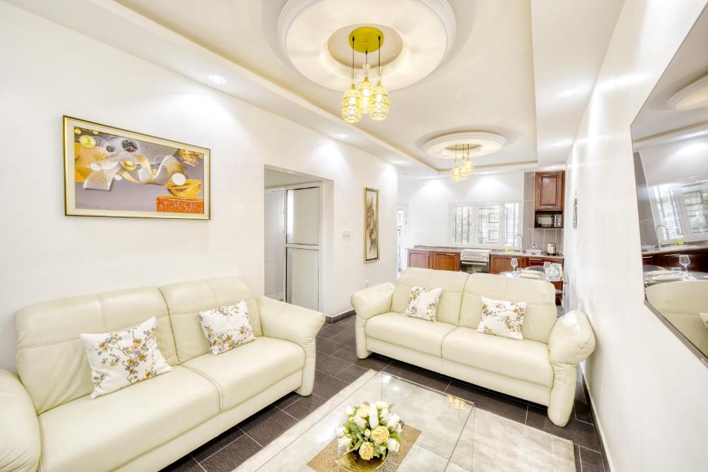 a living room with two white couches and a kitchen at Cosy Home in Douala