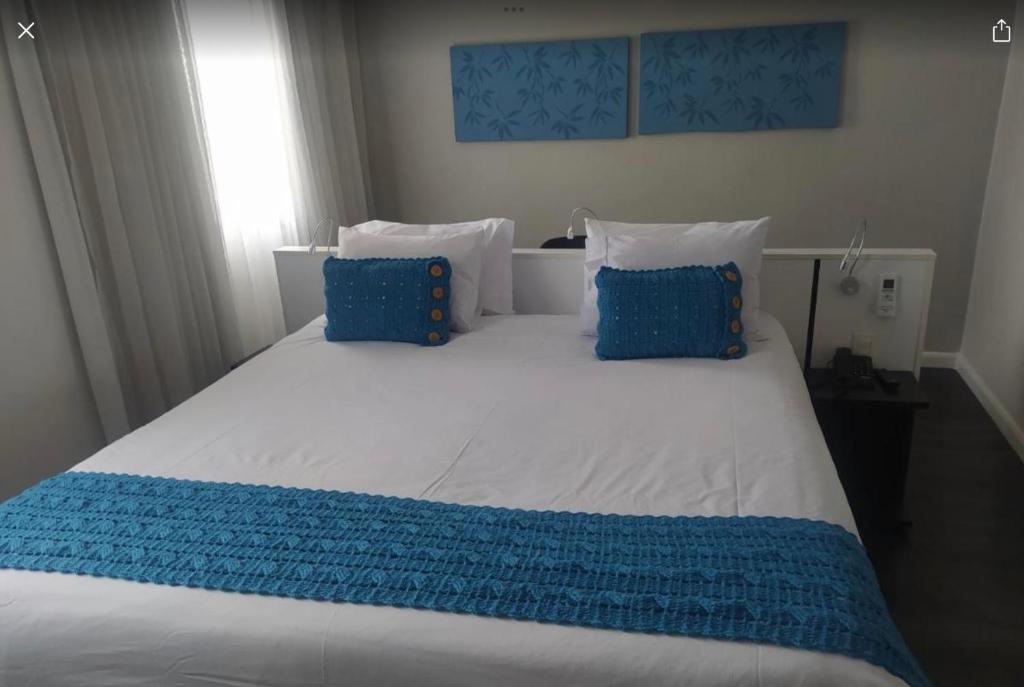 a large bed with blue and white sheets and pillows at Flat Hotel São Paulo, no coração de Moema in São Paulo