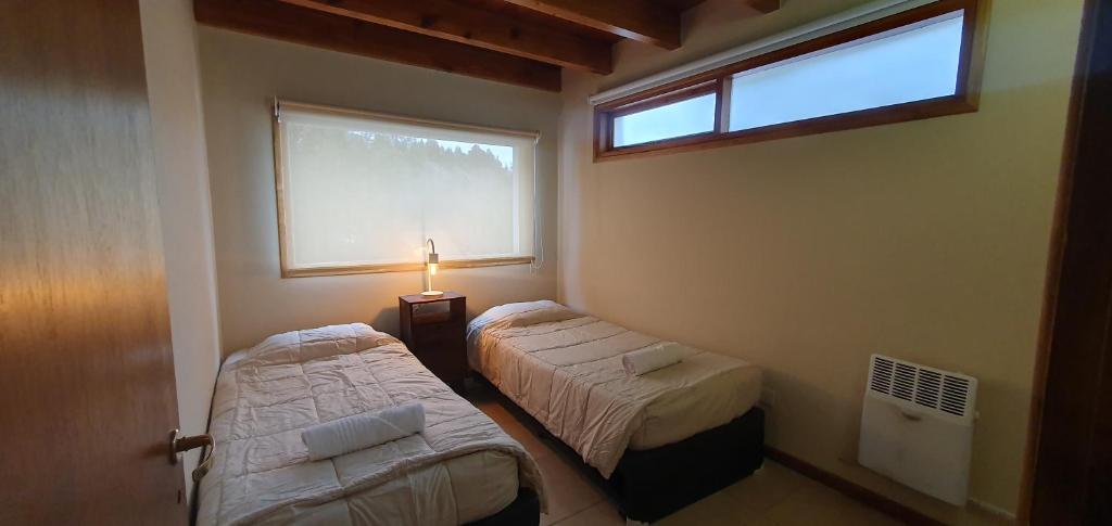 Habitación pequeña con 2 camas y ventana en Cabaña Victoria I en San Martín de los Andes