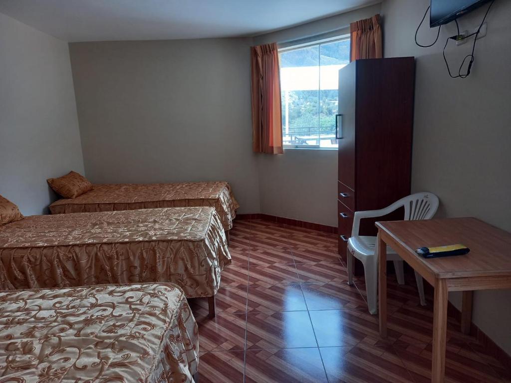 een kamer met 2 bedden, een tafel en een bureau bij hotel bello horizonte de cotahuasi in Cotahuasi