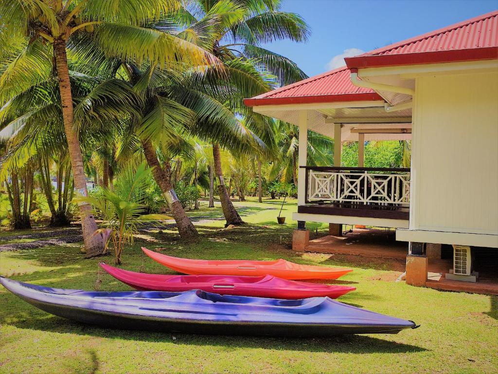 a group of kayaks sitting on the grass near a house at HUAHINE - Hibiscus House in Haapu