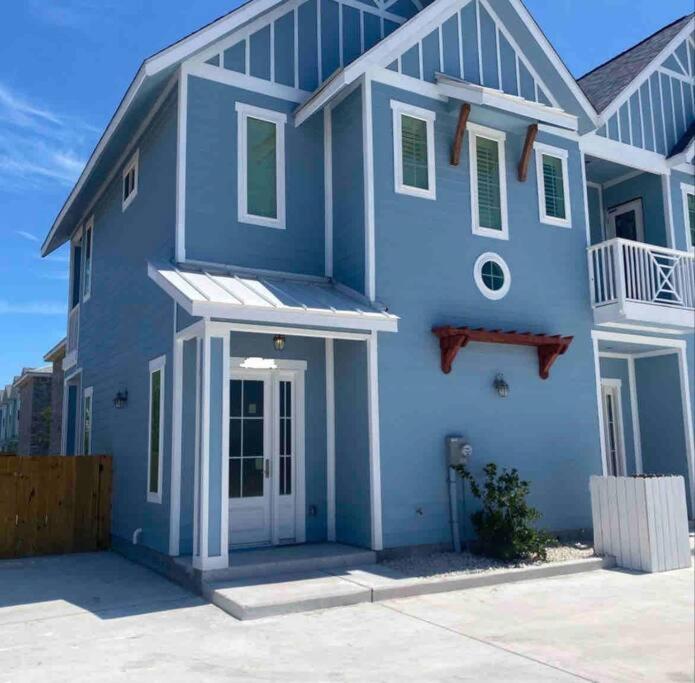 a blue house with a white door on a street at Beach Glass - Island Getaway in Corpus Christi