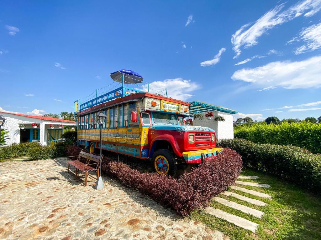 Un bus coloré est exposé dans une cour. dans l'établissement La Querendona Alojamiento Cafetero, à Pereira