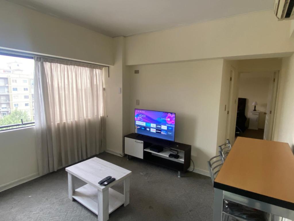 een woonkamer met een flatscreen-tv en een tafel bij Departamento Av San Martín c/ cochera in Mendoza