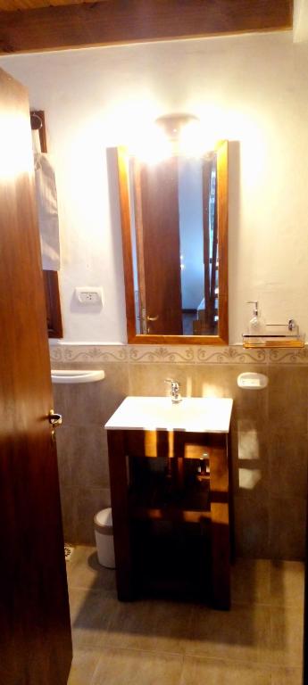een badkamer met een wastafel, een toilet en een spiegel bij POSADA EL ROMANCE in Tandil