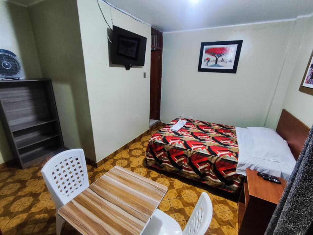 Habitación de hotel con cama, mesa y sillas en Hostal Continental, en Nazca