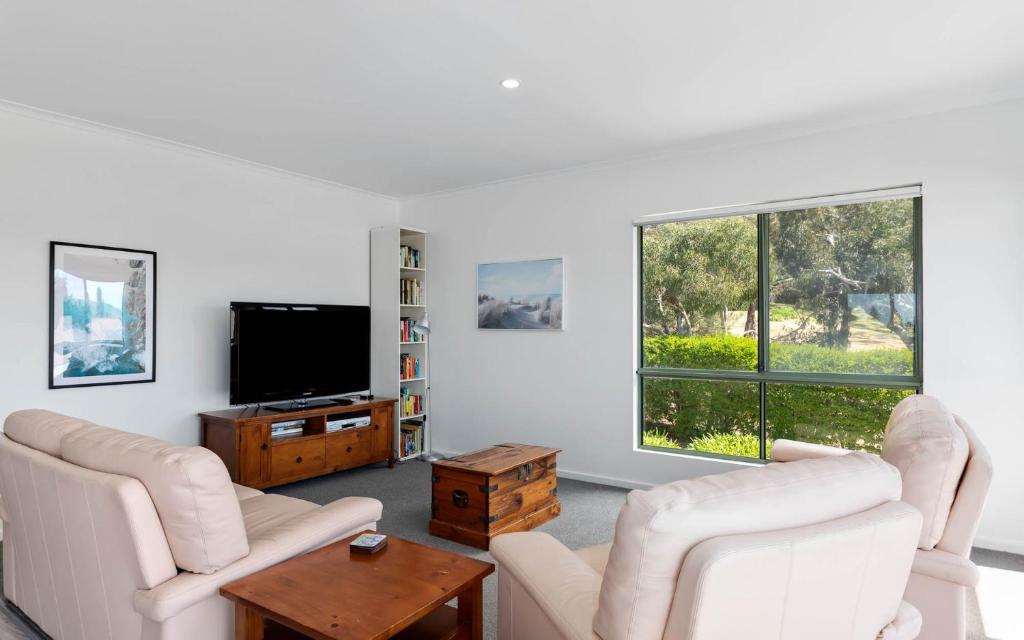 uma sala de estar com mobiliário branco e uma televisão de ecrã plano em Great Family Holiday House in Central Location em Victor Harbor