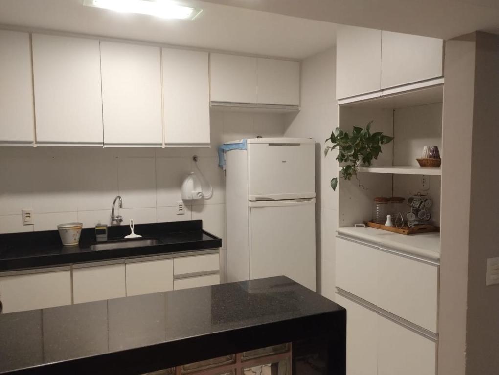 Una cocina con gabinetes blancos y un refrigerador blanco. en Apartamento no centro de Cabo Frio, en Cabo Frío
