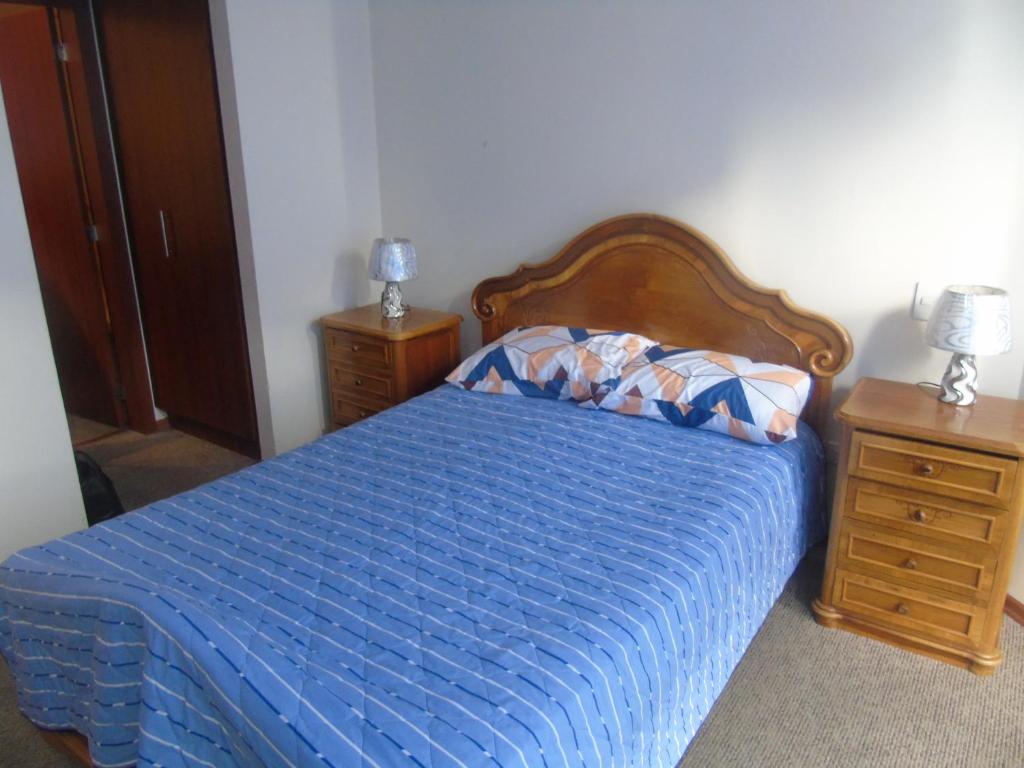 1 dormitorio con 1 cama azul y 2 mesitas de noche en apartamento san martin, en Quito