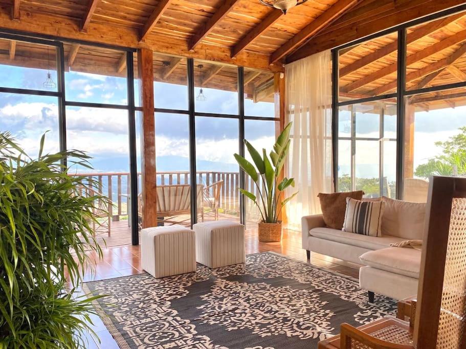 sala de estar con sofá y algunas ventanas en Astonishing view at Poás Volcano slopes: Casa Lili, en Grecia