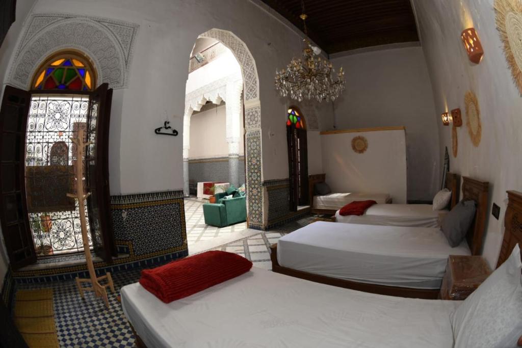 1 dormitorio con 3 camas en una habitación con vidrieras en hostel Dar belghiti, en Fez