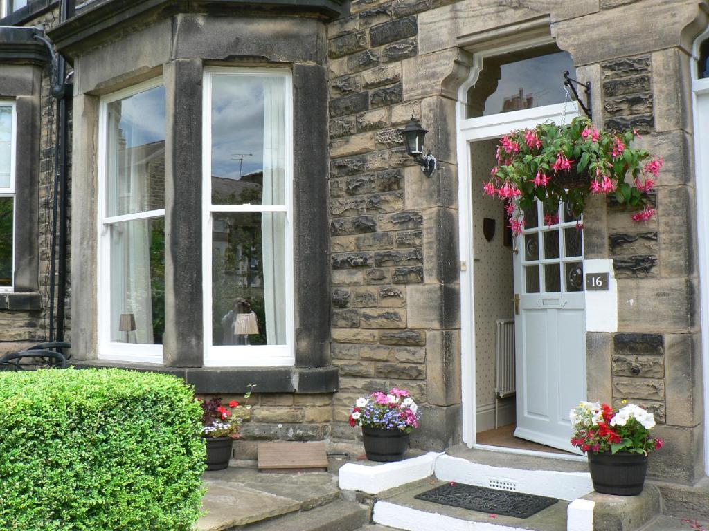 ein Steinhaus mit zwei Fenstern und einer Tür mit Blumen in der Unterkunft 16 Franklin Bijou Boutique in Harrogate