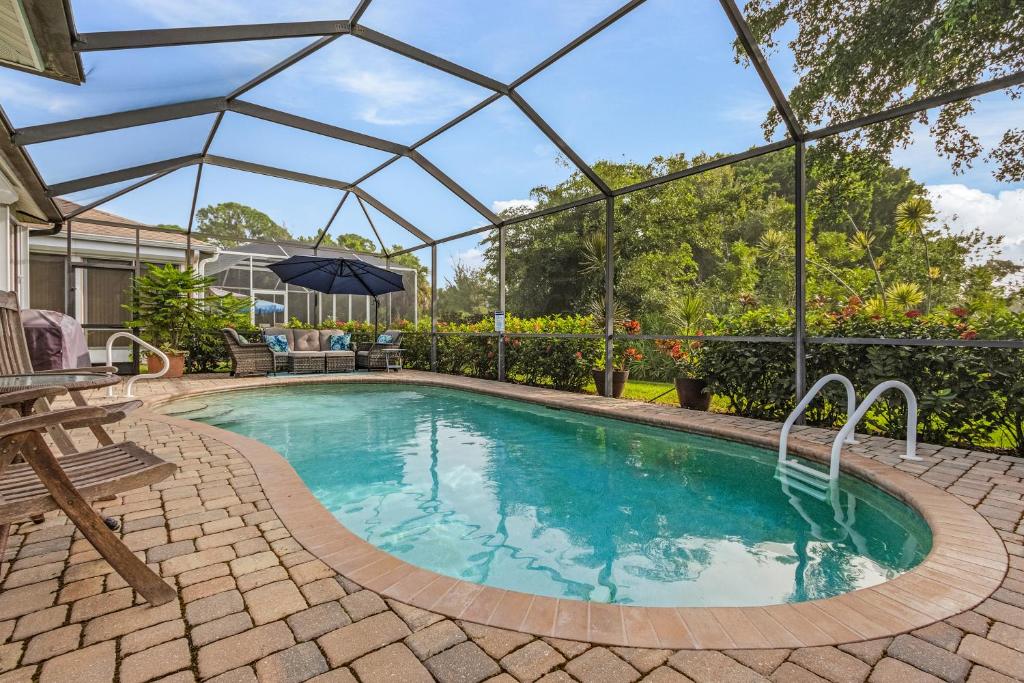 a swimming pool with a pergola next to a house at Sunshine Daydream our Beautiful Monthly Pool Home! home in Fort Myers